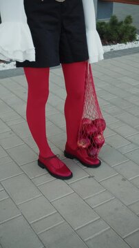 Stylish woman in red tights with apples in mesh bag