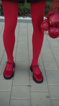 Woman in red tights holding mesh bag with apples