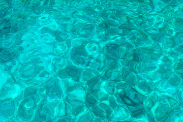 Close-up of crystal clear turquoise water with gentle ripples and sunlit reflections from the Greek islands.