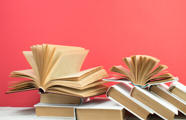 Open books, hardback colorful books on wooden table. Red background. Back to school. Copy space for text. Education business concept.