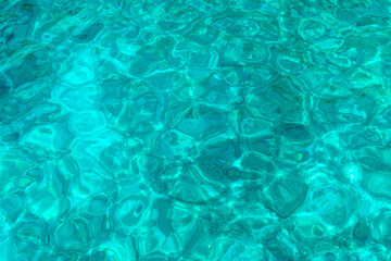Close-up of crystal clear turquoise water with gentle ripples and sunlit reflections from the Greek islands.