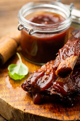 Delicious BBQ baby-back ribs with tangy sauce and a basting brush on wooden cutting board