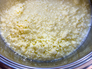 Close-up of curdled eggs and milk while making traditional Slovak Easter cheese “hrudka.” Homemade rustic food preparation in a pot.