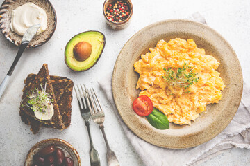 Fresh cooked scrambled eggs in a plate on white background, top view
