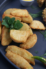 Crispy fried potato wedges garnished with fresh mint leaves, served on a black plate, highlighting the golden crunchy texture, perfect for snack menus, restaurant side dishes, and casual dining promot