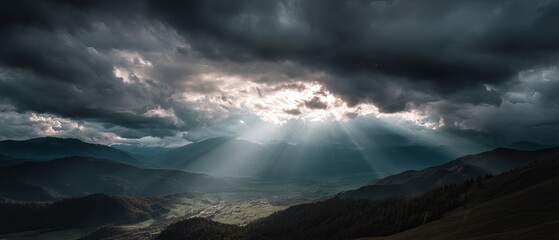 Fototapeta premium Dramatic clouds with rays of sunlight illuminating a mountainous landscape, creating a captivating and serene atmosphere.