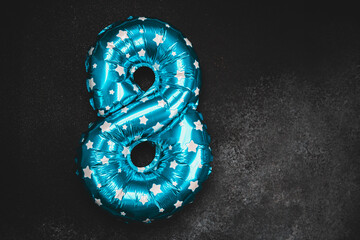 Bright blue star patterned balloon number eight on dark background