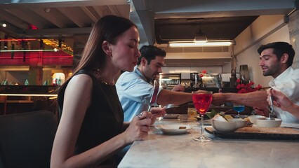 Focusing beautiful woman tasting main course tasty at delicious chef table cuisine with friends taking food together at back side. Theme of celebrating with couple or friend at restaurant. Vinosity.