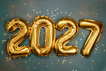 Golden balloons mark the new year 2027 surrounded by sparkling confetti