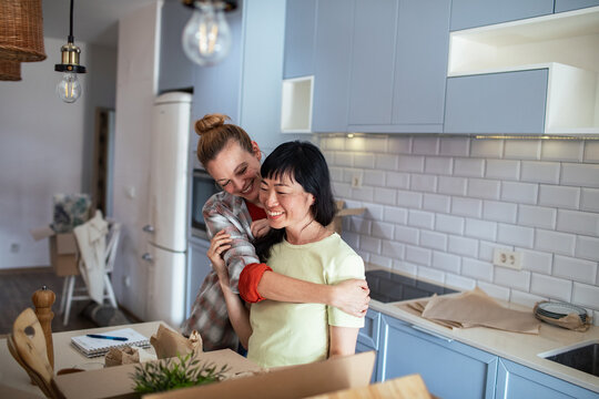 Happy lesbian couple embracing in new home while moving in - Powered by Adobe
