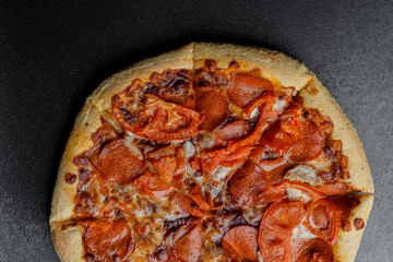 Delicious pepperoni pizza topped with fresh tomatoes on a dark surface