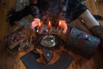 Young witch performing magical ritual with crystal ball and smoking incense. Women's energy