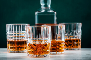 Single malt scotch whiskey in glasses with bottle on dark green background