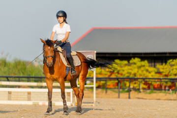 Smart teen girl enjoy to ride horse for exercise and train in the horse riding arena.