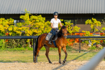 Wide shot of teen girl enjoy to ride horse for exercise and train in the horse riding arena.