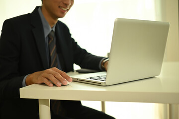 Close-up of a businessman in a suit working on a laptop at a office desk