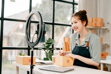 Asian SME businesswoman using smartphone to live stream online shopping at home and work