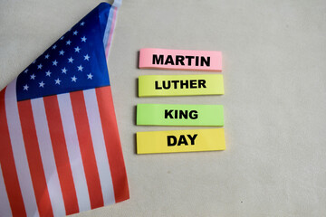 Concept of Martin Luther King day write on sticky notes and the flag the united states isolated on Wooden Table.