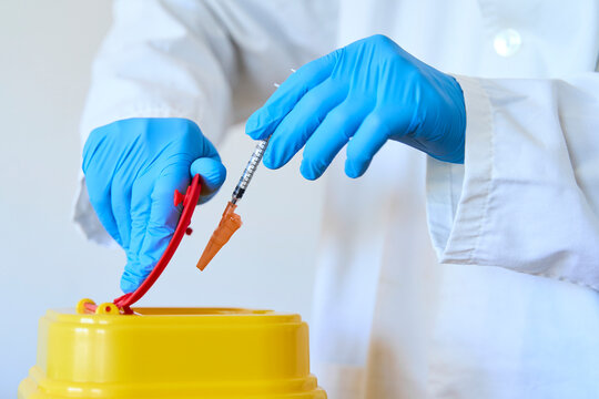 Doctor safely disposing hazardous  medical materials in bin over white background