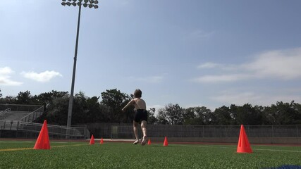 Low angle video of a shirtless young male athlete running conditioning sprints on a football field for training