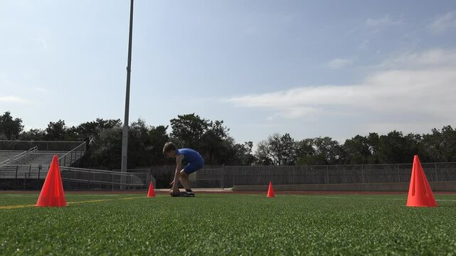 Low angle video of a young male football player running conditioning sprints on the football field for training