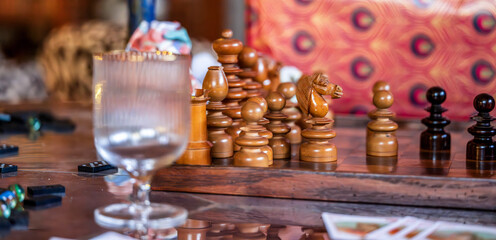 Artistic Chess Set with Dominos, Playing Cards, and Glassware on a Stylish Table