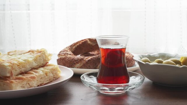 Local Turkish breakfast table Turkish tea, su boregi, green olives and simit bagel	