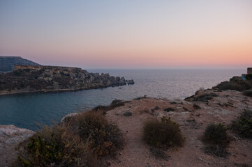 A beautiful sunset over the ocean with a rocky shoreline