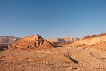 A desert landscape with a large rock in the middle