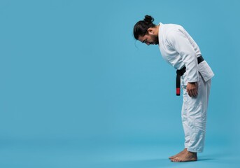 Martial artist bows respectfully wearing gi on a clean backdrop