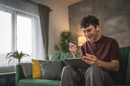 teenager young man sit at home use credit card shopping online