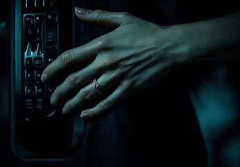 Elegant Hand with Ring Near Phone in Dim Lighting Scene
