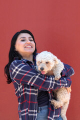 A 25-year-old brunette Latina woman shows off the stray dog ​​she adopted, now her friend and family