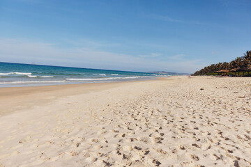 Serenity at the Water's Edge Tranquil Beach Scene with Footprints in the Sand and Blue Sky