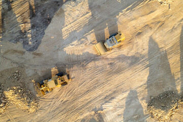 industrial machinery working on a construction site, aerial perspective of excavators and dirt piles. © VicVaz