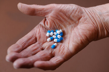 Hand holding blue and white capsules against a neutral background