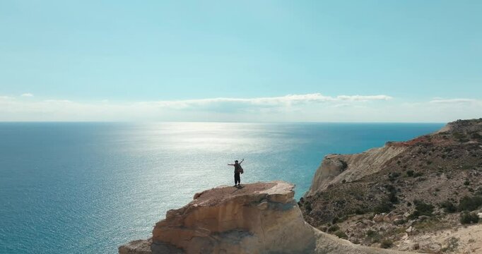 Aerial view of a man on the top of a rock on the birch of the sea. There is a feeling of freedom at the top after hiking along mountain trails on the birch ocean, tourism and roads. High quality 4k 