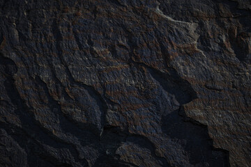 A textured stone background with chiaroscuro lighting, showcasing a brutal, monolithic rock formation. Cracks and fragments highlight its geological power, perfect for design templates or science