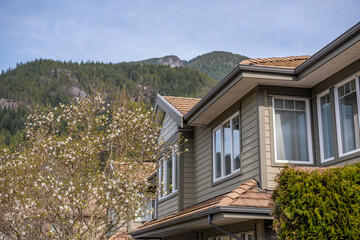 Top of grey stucco luxury house with shingle roof, trees and nice windows in Spring in Vancouver, Canada, North America. Day time on April 2025.