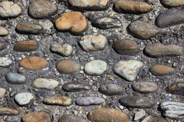 Close-up of cobblestone pavement texture with natural stones in dry soil