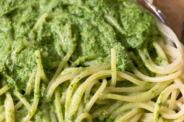 Delicious spaghetti coated in vibrant green pesto sauce, served in a bowl, showcasing fresh ingredients. Ideal for food blogs and culinary projects.
