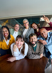 Vertical. Multicultural coworkers laughing during a lively office meeting, showcasing teamwork,...