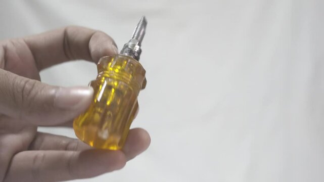 Hand Holding a Small Screwdriver with a Transparent Orange Handle. Classic Stubby Screwdriver