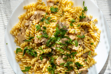 Italian pasta with creamy mushrooms and parsley on white plate in close-up