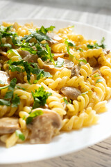 Italian pasta with creamy mushrooms and parsley on white plate in close-up