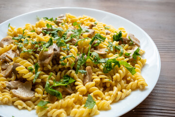 Italian pasta with creamy mushrooms and parsley on white plate in close-up