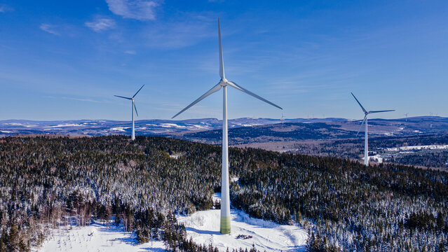 Wind turbines on top of snow-capped mountains on a beautiful winter day
