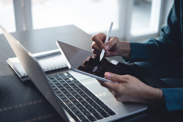 Woman using stylus pen on digital tablet with laptop computer, notebook on office table. Student studying online from home. Graphic designer, illustrator hand drawing on tablet via mobile app