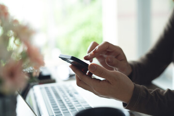 Close up, business woman using mobile phone with laptop computer on office table. Woman using smartphone for online shopping and internet banking, social media marketing