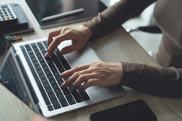 Close up of business woman working on laptop computer, searching and surfing the internet on office...